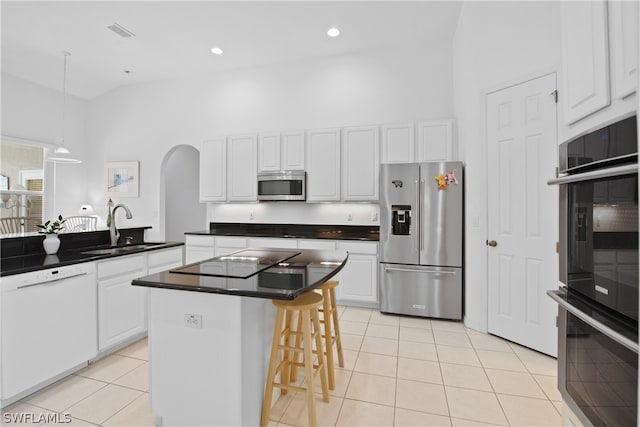 kitchen with stainless steel appliances, sink, a kitchen island, high vaulted ceiling, and white cabinetry