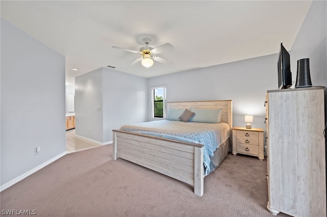 carpeted bedroom with ensuite bath and ceiling fan