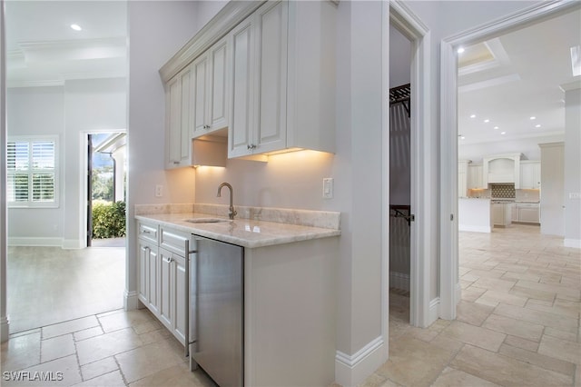 kitchen with light stone countertops, a tray ceiling, crown molding, sink, and a high ceiling