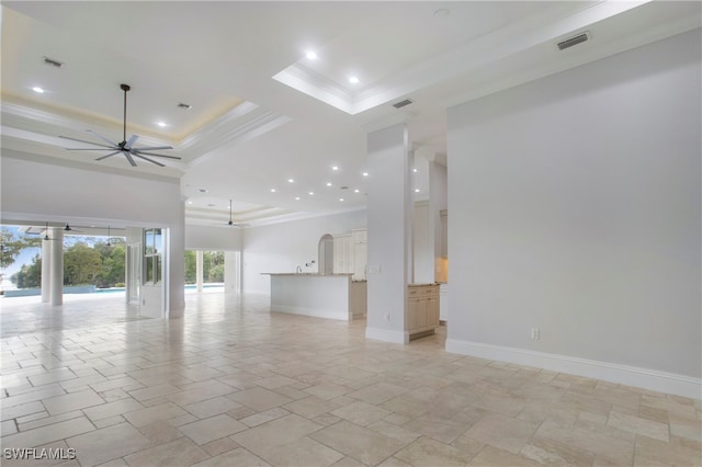 unfurnished living room featuring a tray ceiling, crown molding, and ceiling fan