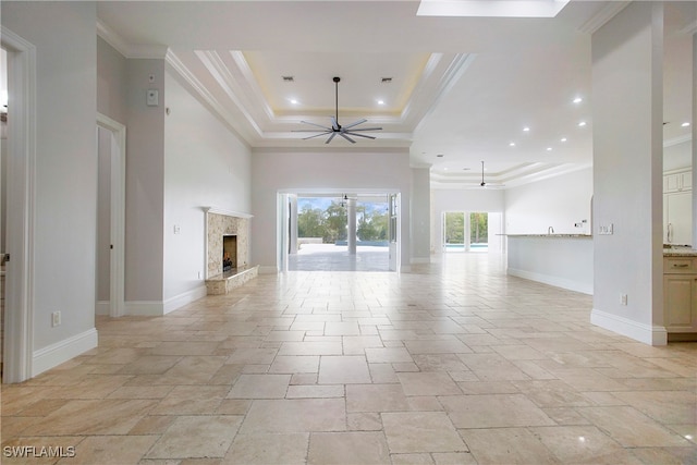 unfurnished living room featuring crown molding, a premium fireplace, ceiling fan, and a raised ceiling