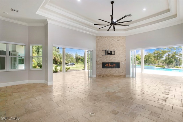 unfurnished living room featuring a tray ceiling, a high ceiling, ceiling fan, and a large fireplace