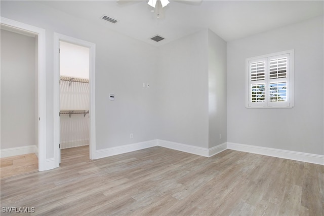 unfurnished bedroom featuring a closet, ceiling fan, a spacious closet, and light hardwood / wood-style flooring