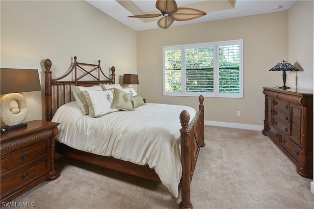 carpeted bedroom with a raised ceiling and ceiling fan