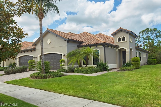 mediterranean / spanish home featuring a garage and a front lawn