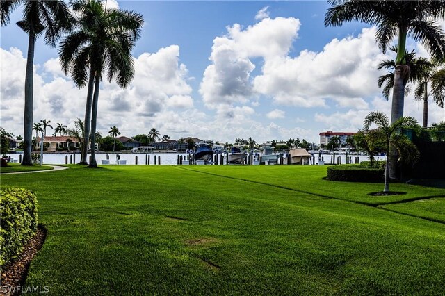 surrounding community with a water view, a dock, and a yard