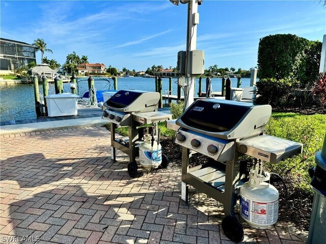 view of patio / terrace featuring a water view, a dock, and area for grilling