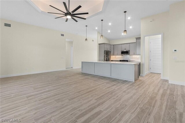 kitchen featuring decorative light fixtures, ceiling fan, stainless steel appliances, an island with sink, and gray cabinetry