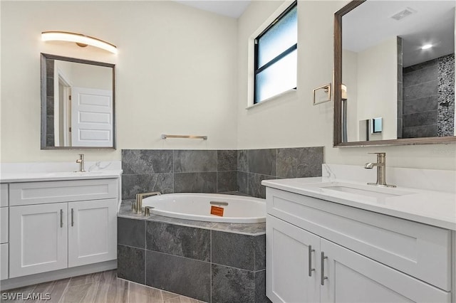 bathroom featuring vanity and tiled bath