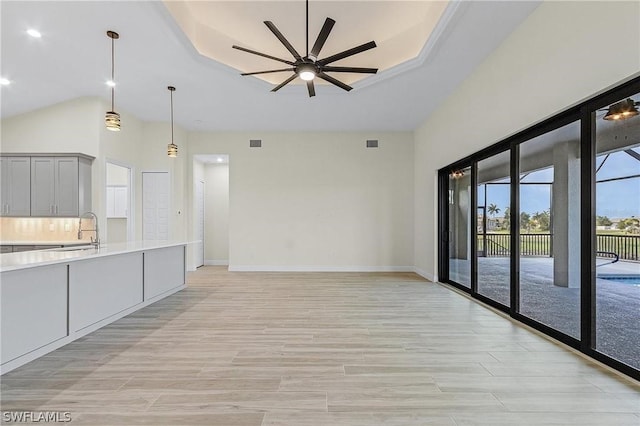 kitchen featuring hanging light fixtures, sink, light hardwood / wood-style floors, and a tray ceiling