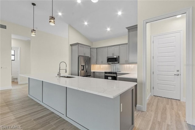 kitchen with tasteful backsplash, pendant lighting, sink, a center island with sink, and appliances with stainless steel finishes