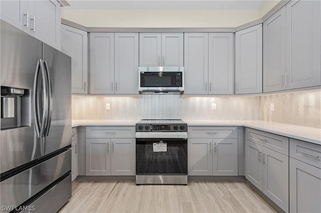 kitchen featuring gray cabinets, appliances with stainless steel finishes, and backsplash