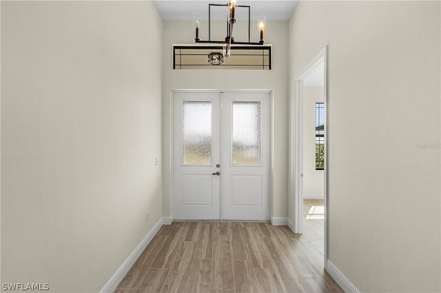 doorway with light hardwood / wood-style floors and a notable chandelier