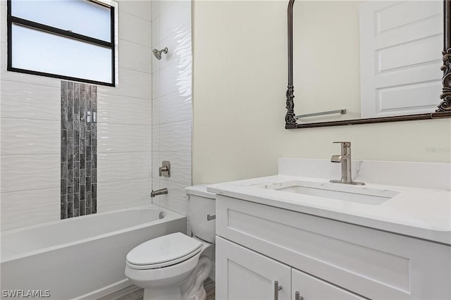 full bathroom featuring tiled shower / bath combo, toilet, and vanity