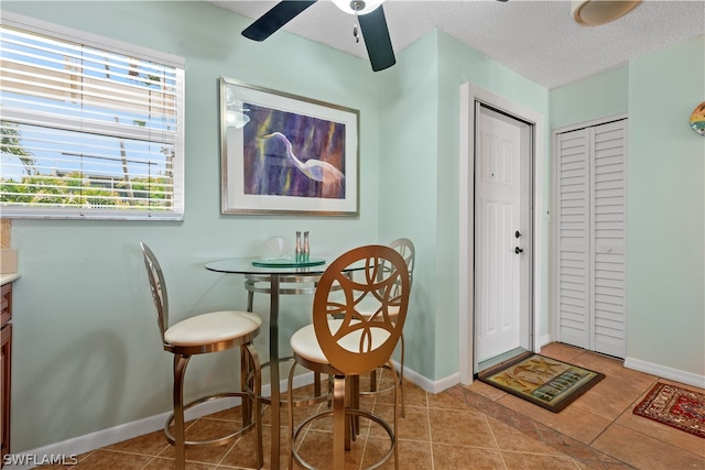 tiled dining area featuring ceiling fan and a textured ceiling