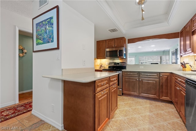 kitchen with appliances with stainless steel finishes, kitchen peninsula, tasteful backsplash, a tray ceiling, and light tile patterned flooring