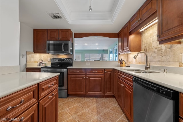 kitchen with appliances with stainless steel finishes, a tray ceiling, sink, and backsplash