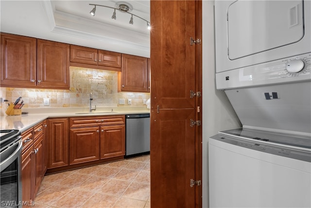 kitchen with appliances with stainless steel finishes, stacked washing maching and dryer, rail lighting, sink, and light tile patterned flooring