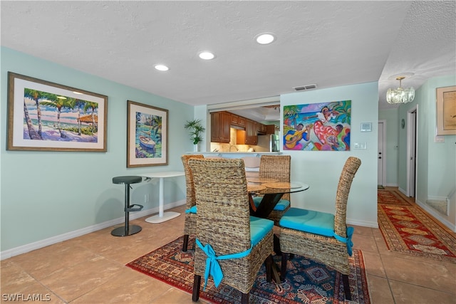 dining space featuring a textured ceiling, a chandelier, and light tile patterned floors