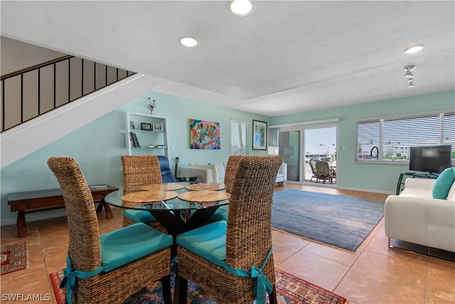 dining space with a textured ceiling and light tile patterned floors