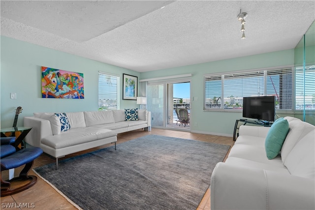 living room with a textured ceiling, tile patterned floors, and a healthy amount of sunlight