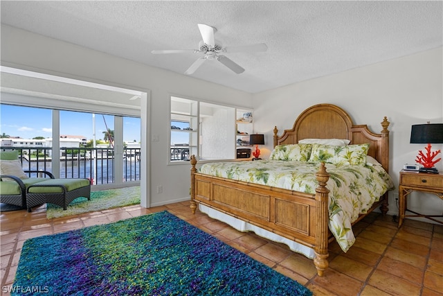 tiled bedroom featuring multiple windows, access to outside, a textured ceiling, and ceiling fan