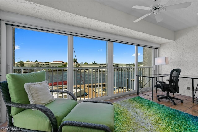 sunroom / solarium featuring ceiling fan and a water view