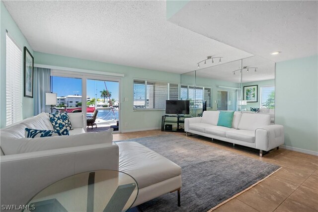 living room with rail lighting, a textured ceiling, and tile patterned floors