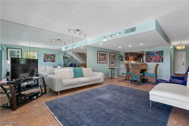 living room with a textured ceiling, light tile patterned floors, and track lighting