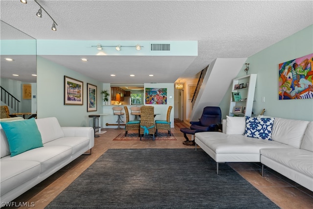 tiled living room featuring rail lighting and a textured ceiling