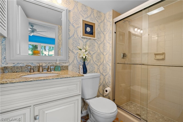 bathroom featuring ceiling fan, a shower with door, toilet, and vanity