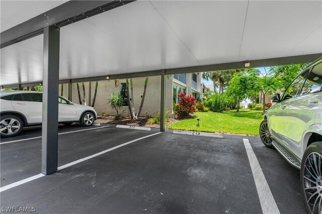 view of parking / parking lot featuring a lawn and a carport