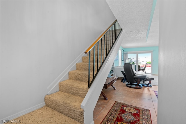 staircase with a textured ceiling and tile patterned floors