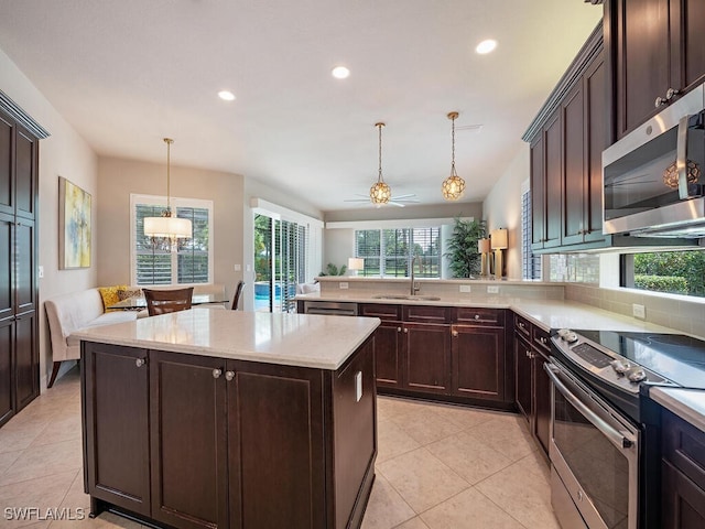 kitchen featuring pendant lighting, a center island, kitchen peninsula, stainless steel appliances, and dark brown cabinets