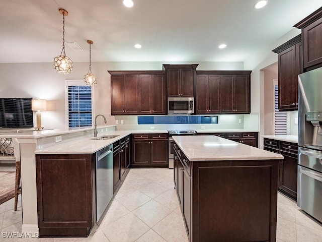 kitchen with sink, dark brown cabinets, hanging light fixtures, appliances with stainless steel finishes, and kitchen peninsula