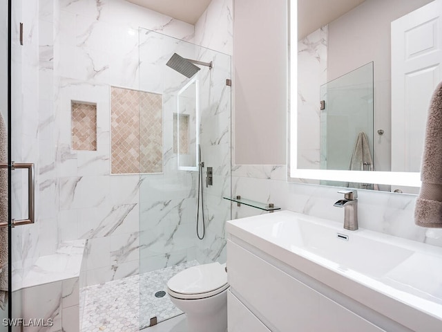 bathroom with vanity, toilet, a shower with door, and tile walls