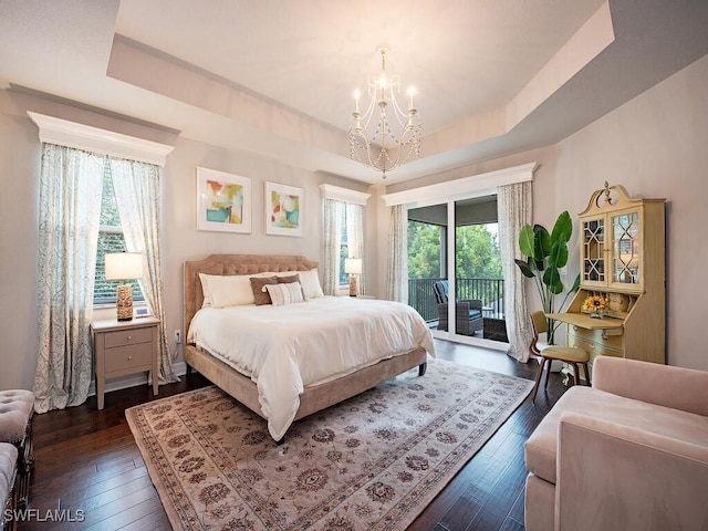 bedroom featuring a chandelier, dark hardwood / wood-style flooring, a raised ceiling, and access to outside