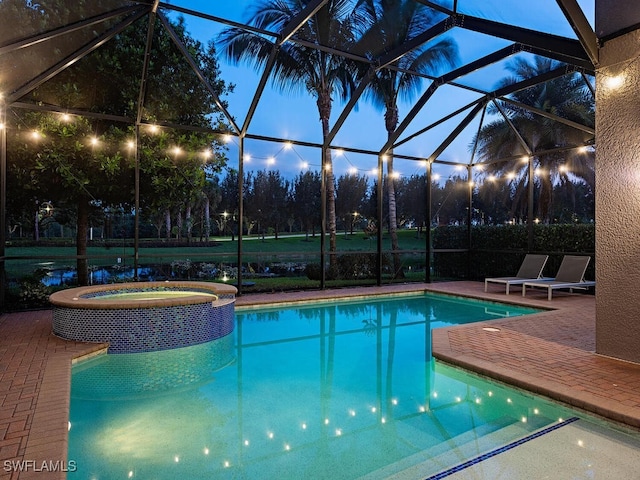 view of pool with an in ground hot tub, glass enclosure, and a patio