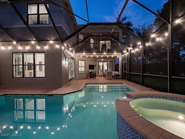 pool at dusk featuring a patio and a lanai