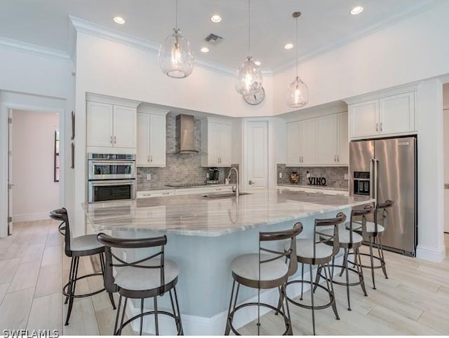 kitchen featuring a large island, wall chimney exhaust hood, sink, and appliances with stainless steel finishes