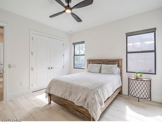 bedroom with a closet, light hardwood / wood-style flooring, and ceiling fan