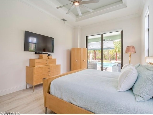 bedroom featuring access to exterior, light hardwood / wood-style floors, ceiling fan, and a tray ceiling