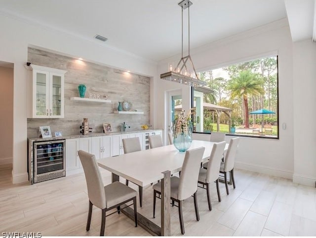 dining room with bar area, wine cooler, and ornamental molding