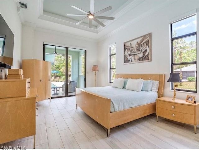 bedroom featuring access to exterior, ceiling fan, a raised ceiling, and multiple windows