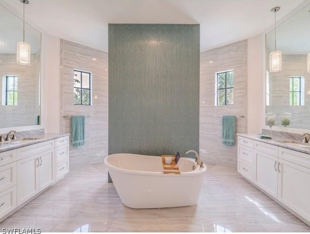 bathroom with a bathtub, plenty of natural light, tile walls, and vanity