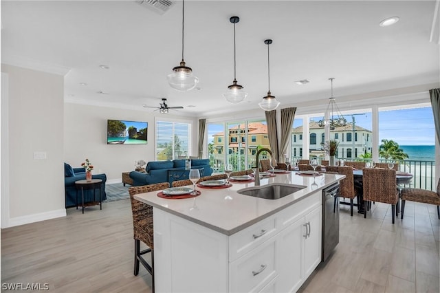 kitchen featuring ceiling fan, a kitchen island with sink, sink, dishwasher, and white cabinetry