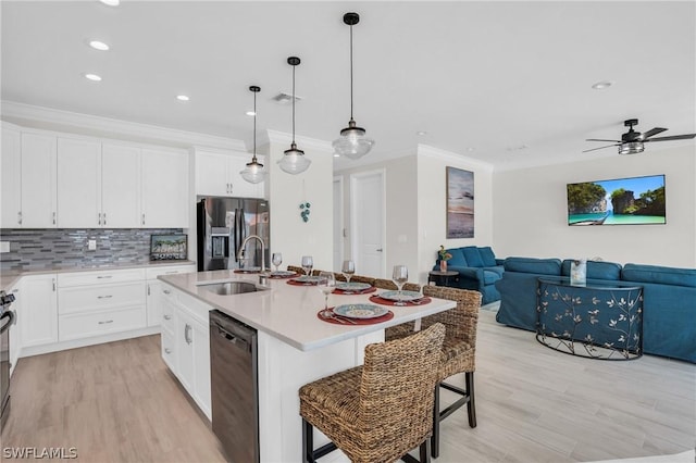 kitchen with a kitchen bar, appliances with stainless steel finishes, sink, white cabinetry, and an island with sink