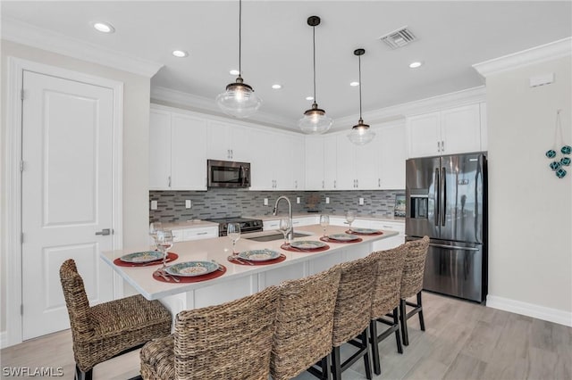 kitchen with white cabinetry, sink, an island with sink, and stainless steel appliances