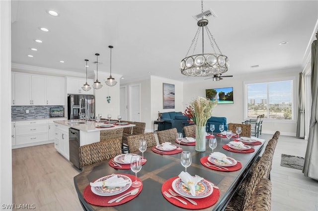 dining space featuring ceiling fan with notable chandelier, light hardwood / wood-style floors, ornamental molding, and sink