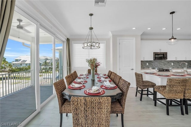 dining space featuring crown molding, sink, and ceiling fan with notable chandelier